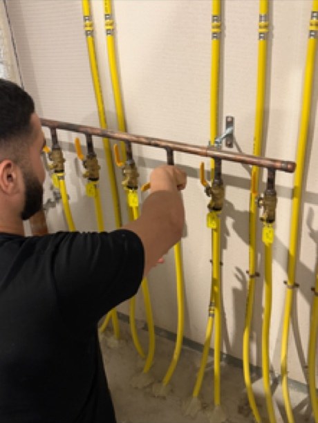 Plumber working on a copper header with brass lever isolation valves