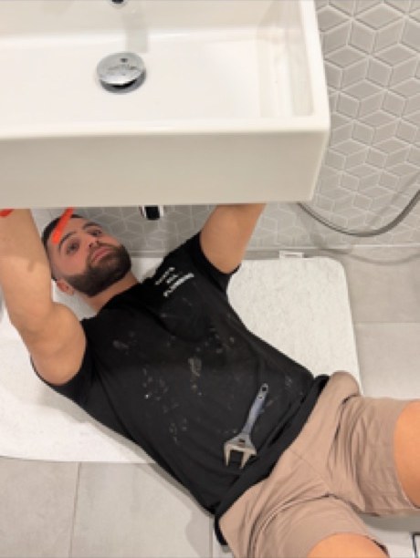 Plumber working under a newly installed wall-hung basin